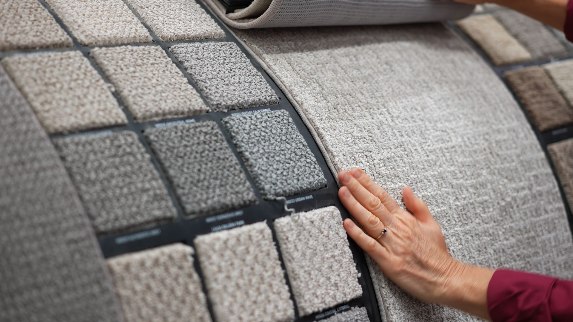 A woman is touching some carpet samples.