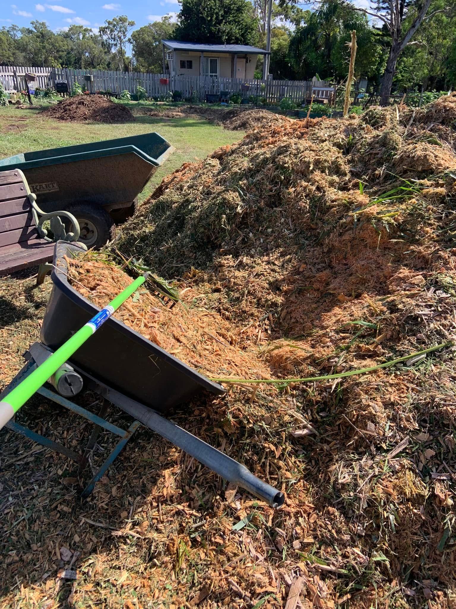 A Yellow Garden Wagon Filled With Dark Mulch — Barlows Tree Services in Rockhampton, QLD