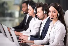 People in suits wearing headsets and using laptops in an office, one smiling.