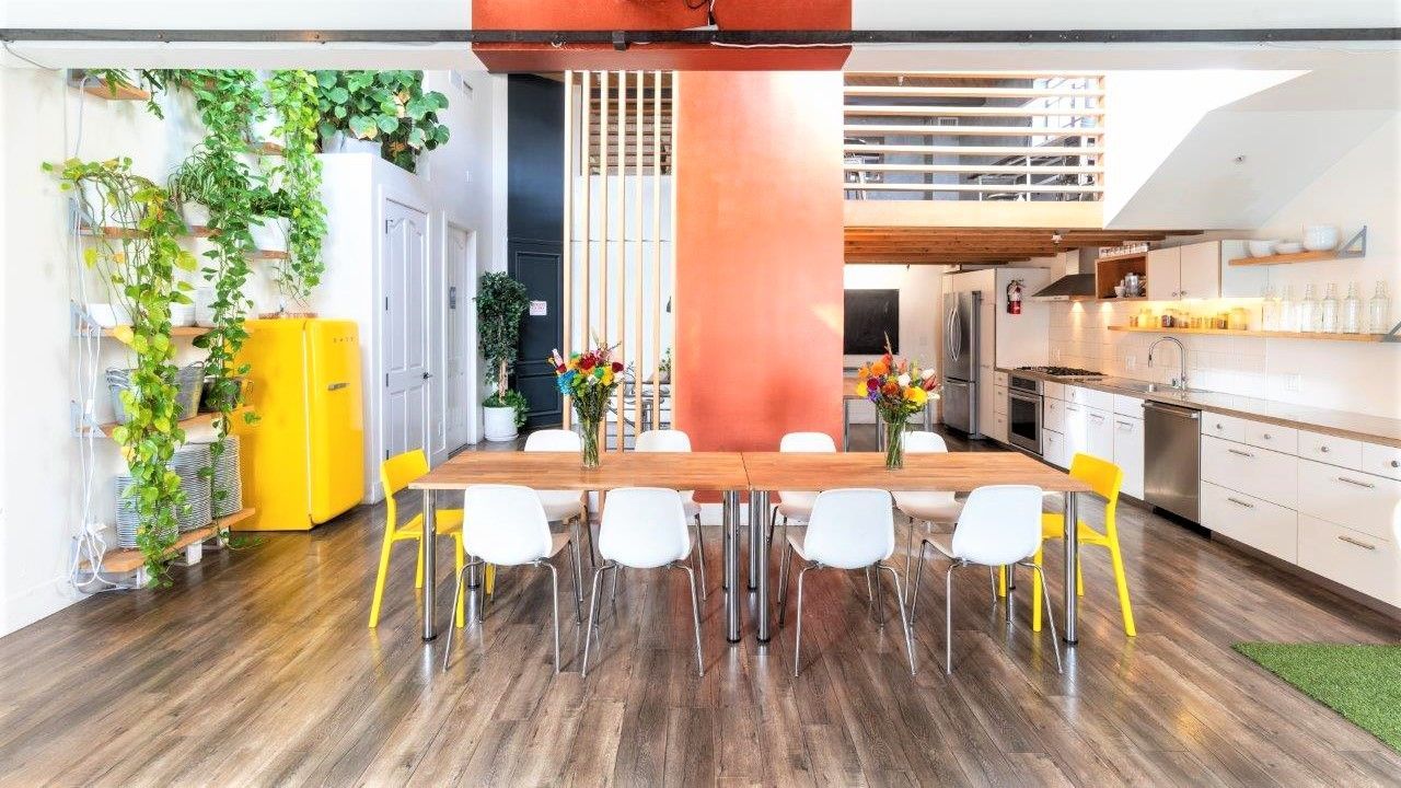 A dining room with a long table and chairs and a yellow refrigerator.