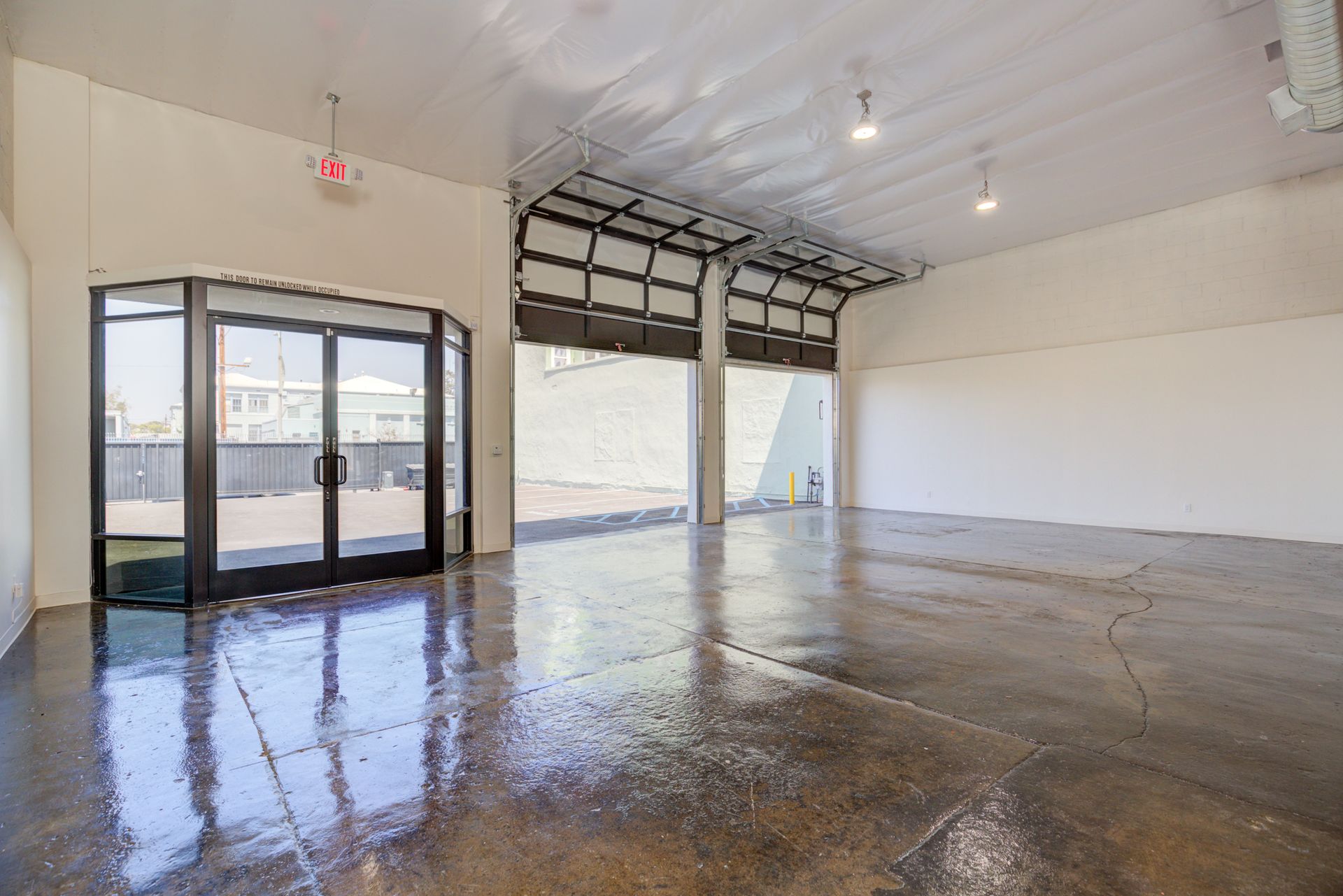A large empty room with a concrete floor and a garage door.
