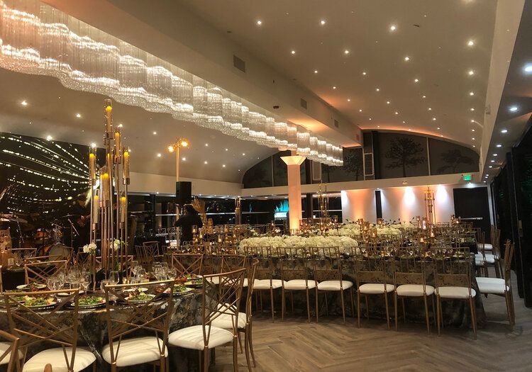 A large room with tables and chairs set up for a wedding reception.
