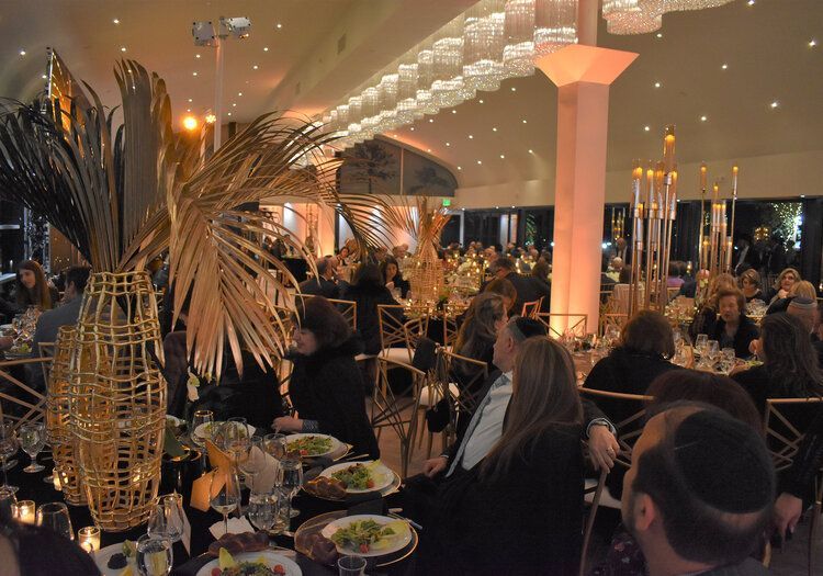 A large room filled with people sitting at tables with plates of food