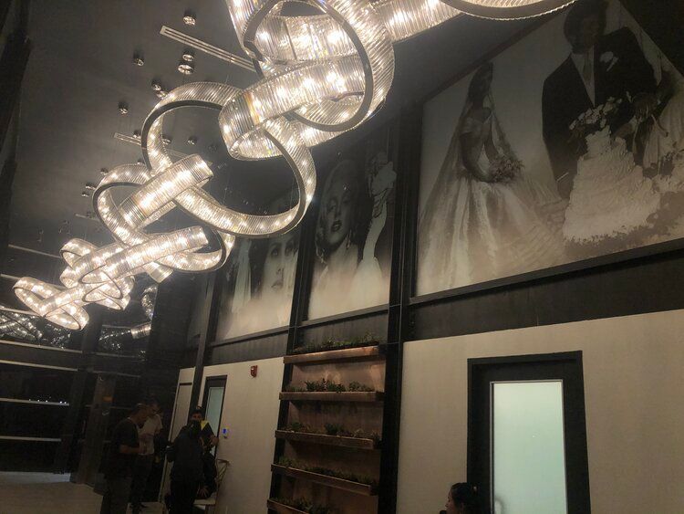 A large chandelier is hanging from the ceiling of a room with a picture of a bride and groom on the wall.