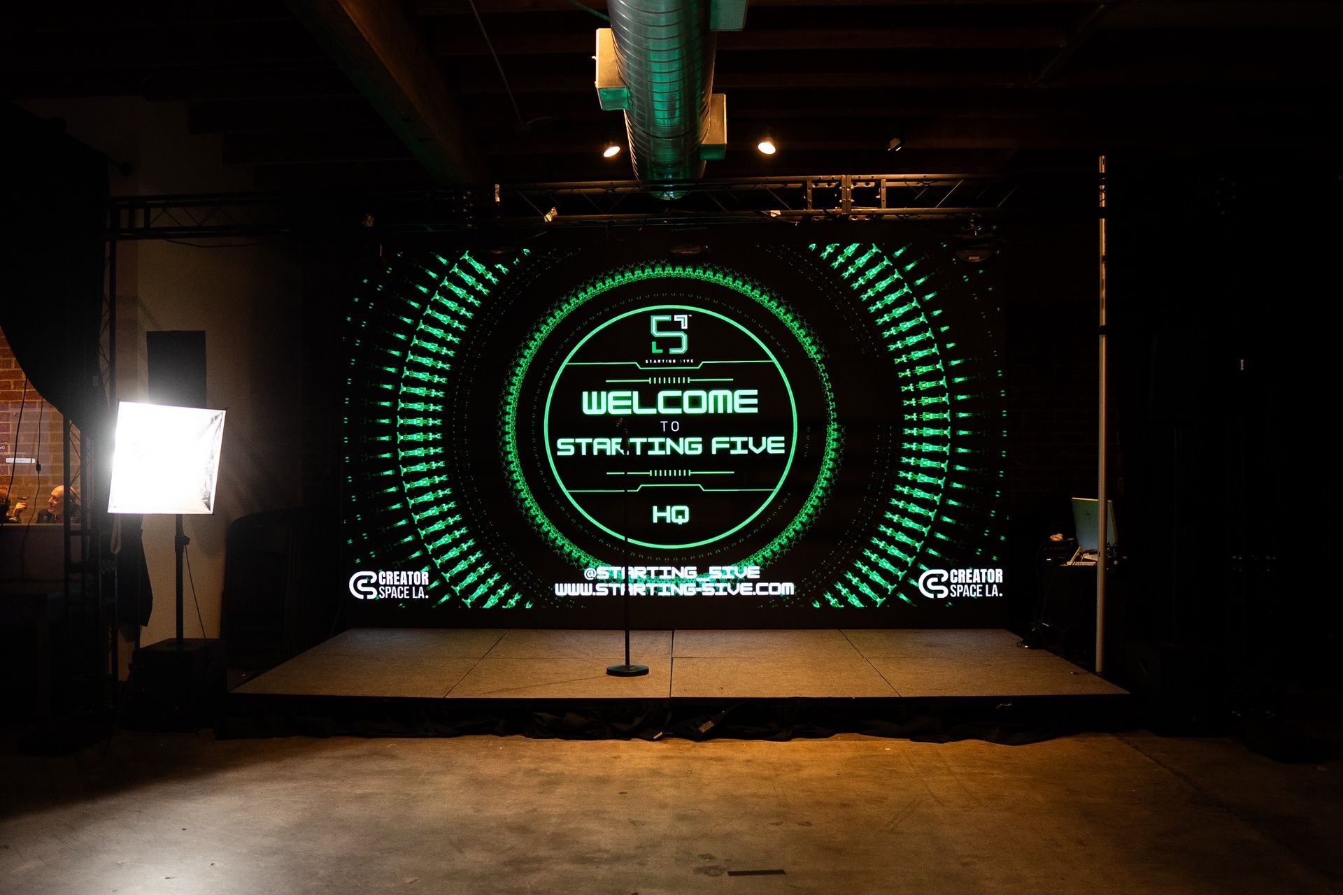 A brightly lit stage features a large LED screen displaying 