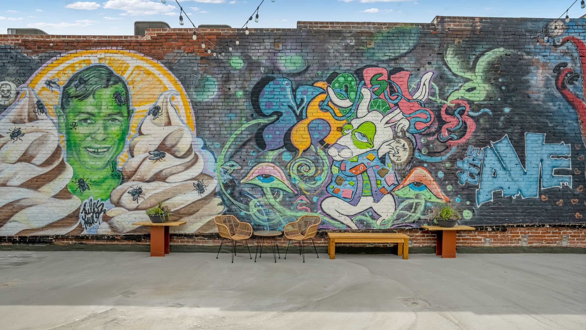 A brick wall with graffiti on it and a bench in front of it.