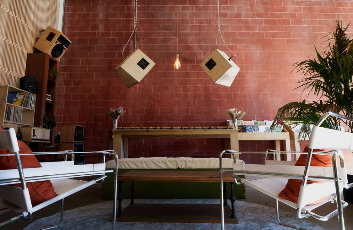 A living room with two chairs a table and a brick wall