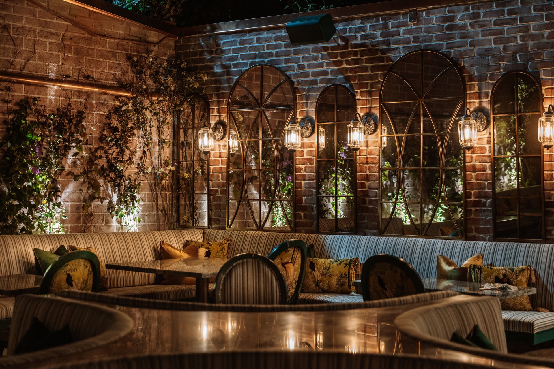 A restaurant with tables and chairs in front of a brick wall.