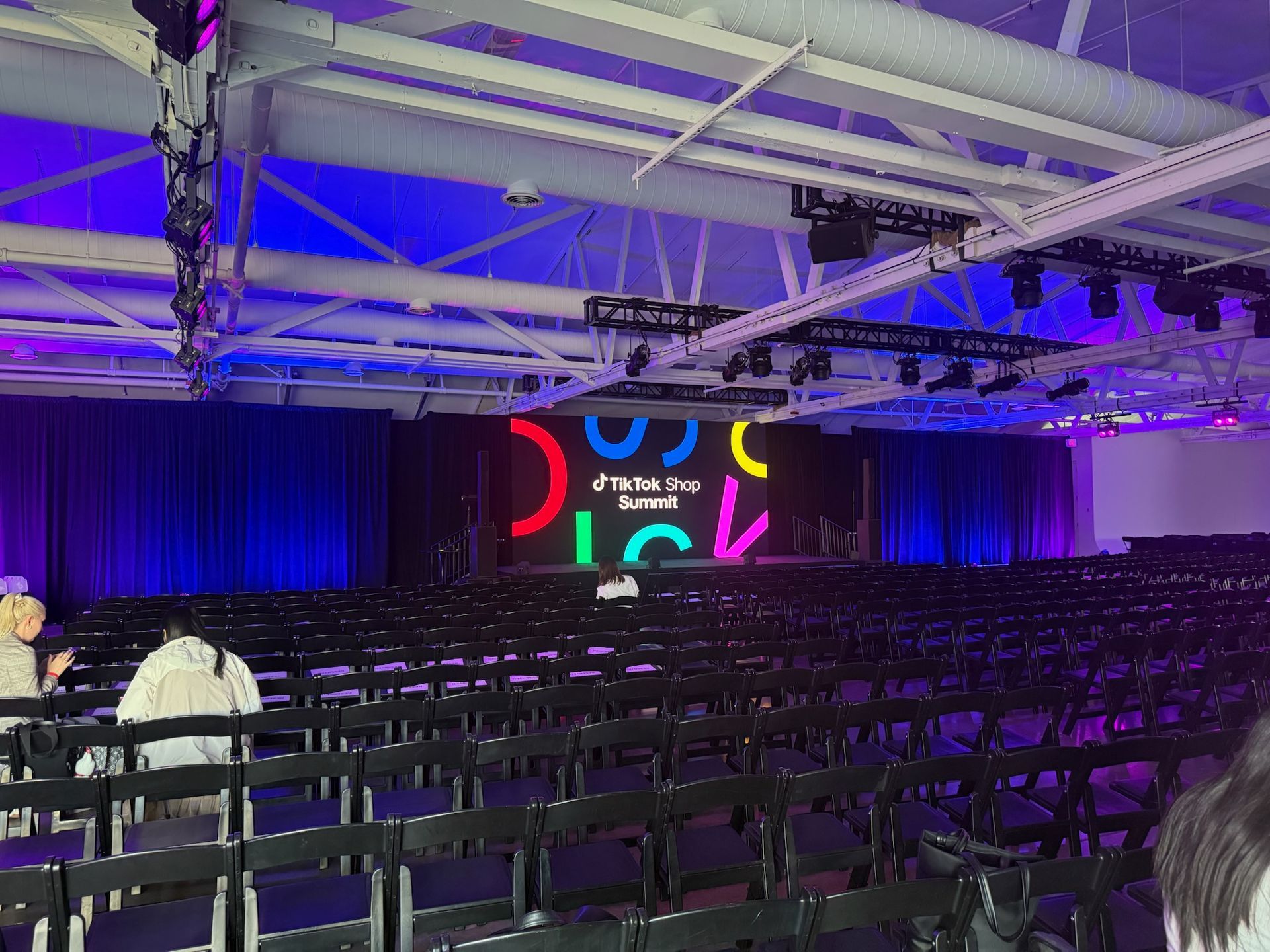Rows of chairs face a stage with a brightly lit 