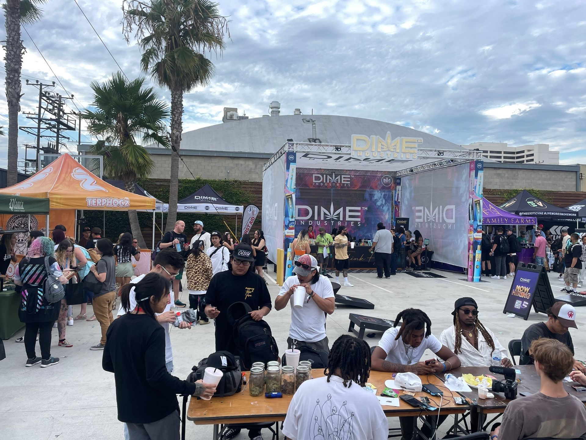 People gather around tables at an outdoor event featuring a 