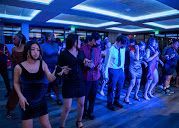 A group of people dancing in a dimly lit, blue-hued room with geometric ceiling panels.