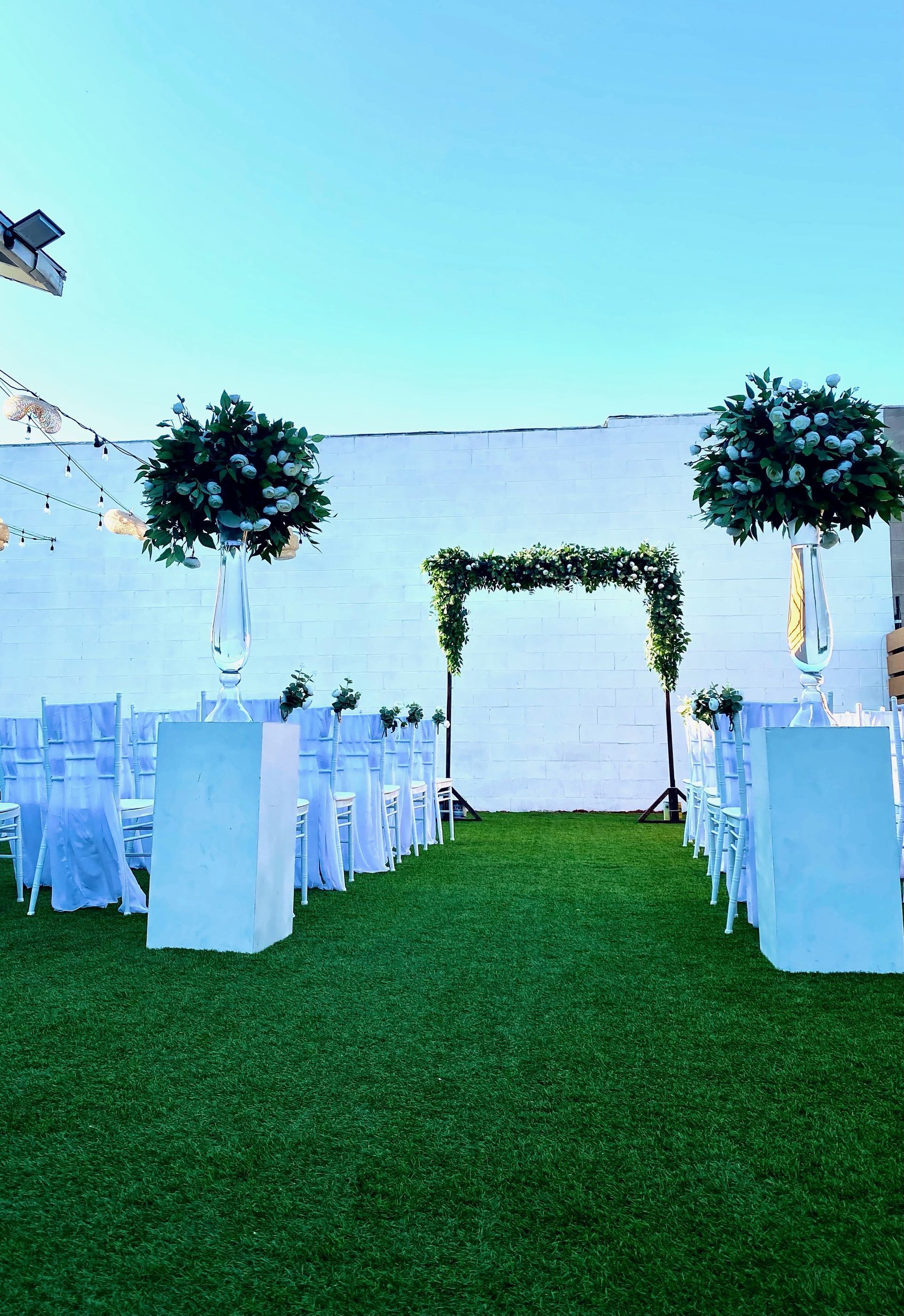 A wedding ceremony is taking place on a lush green lawn.