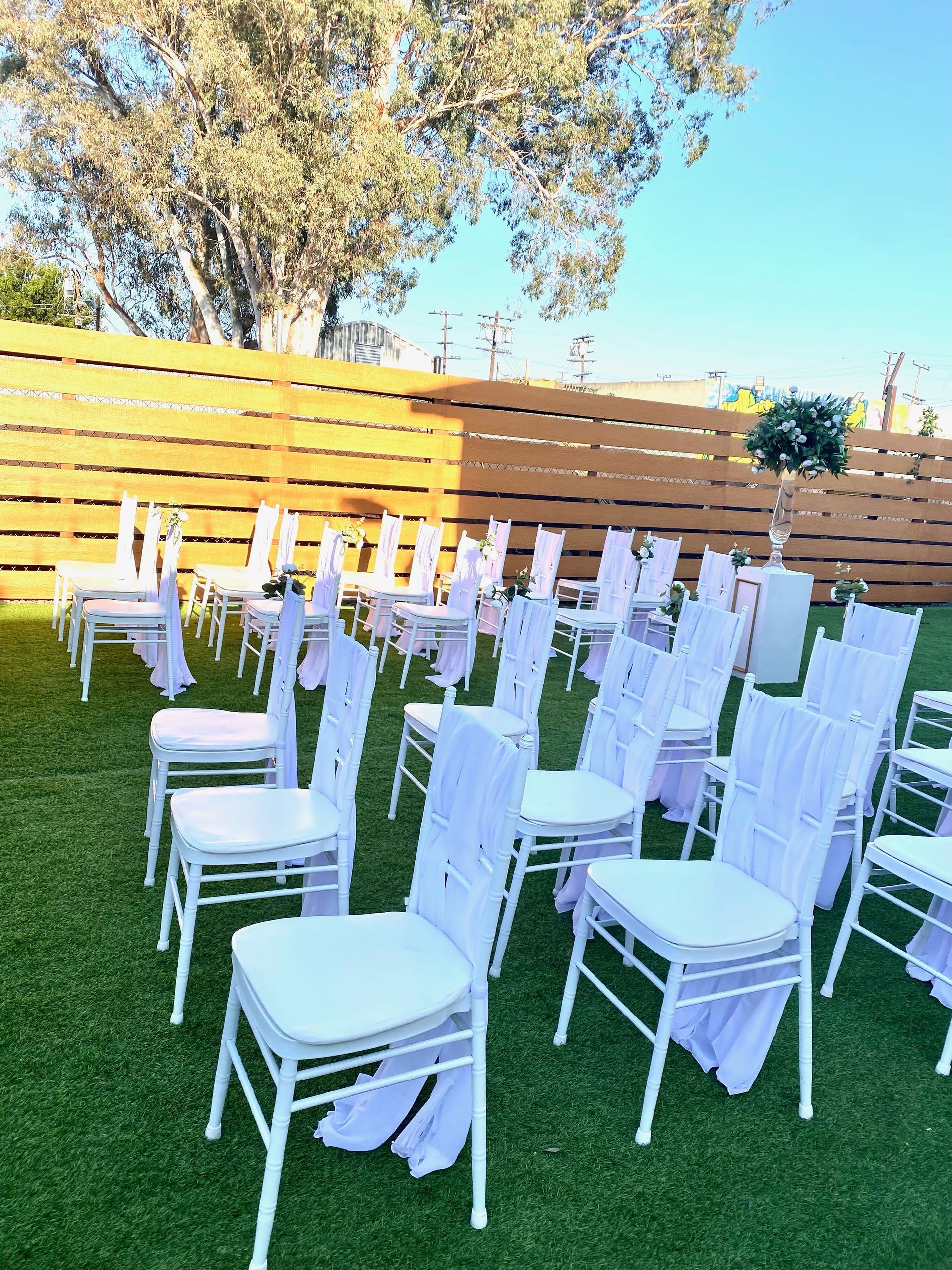 A row of white chairs sitting on top of a lush green field.