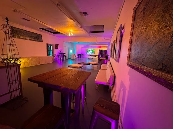 A large room with tables and chairs and purple lights on the walls.