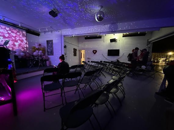 A large room with rows of folding chairs and a projector screen.