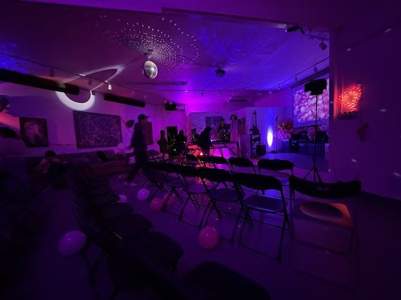 A group of people are standing in a room with purple lights on the ceiling.