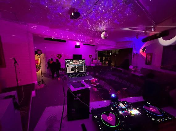 A dj is playing music in a room with purple lights.