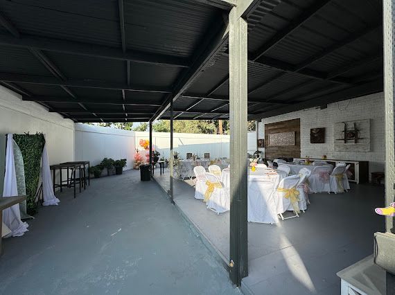 A large room with tables and chairs under a covered area.