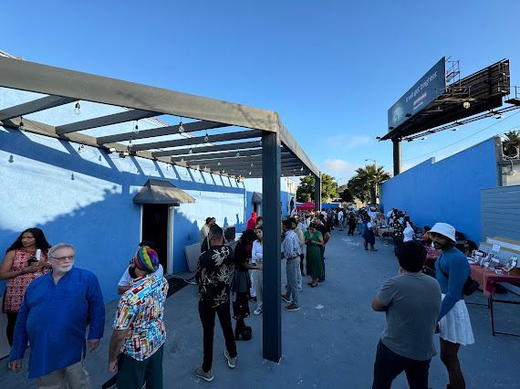 A group of people are standing in front of a blue building.