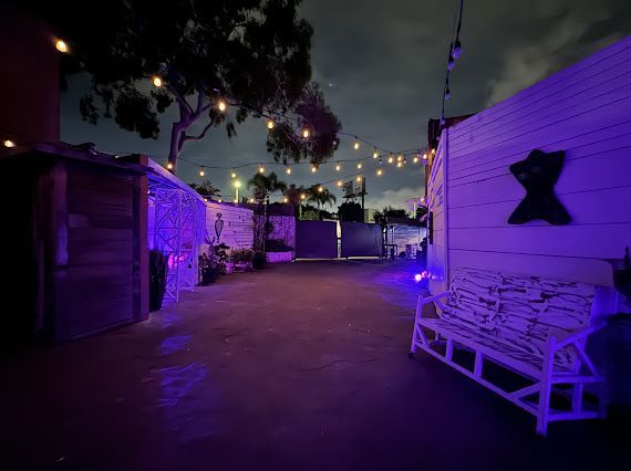 A white bench is sitting in front of a building with purple lights.