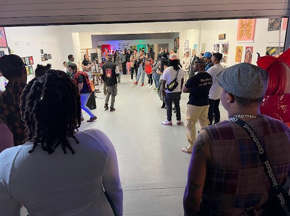A group of people are standing in a room and looking at something.