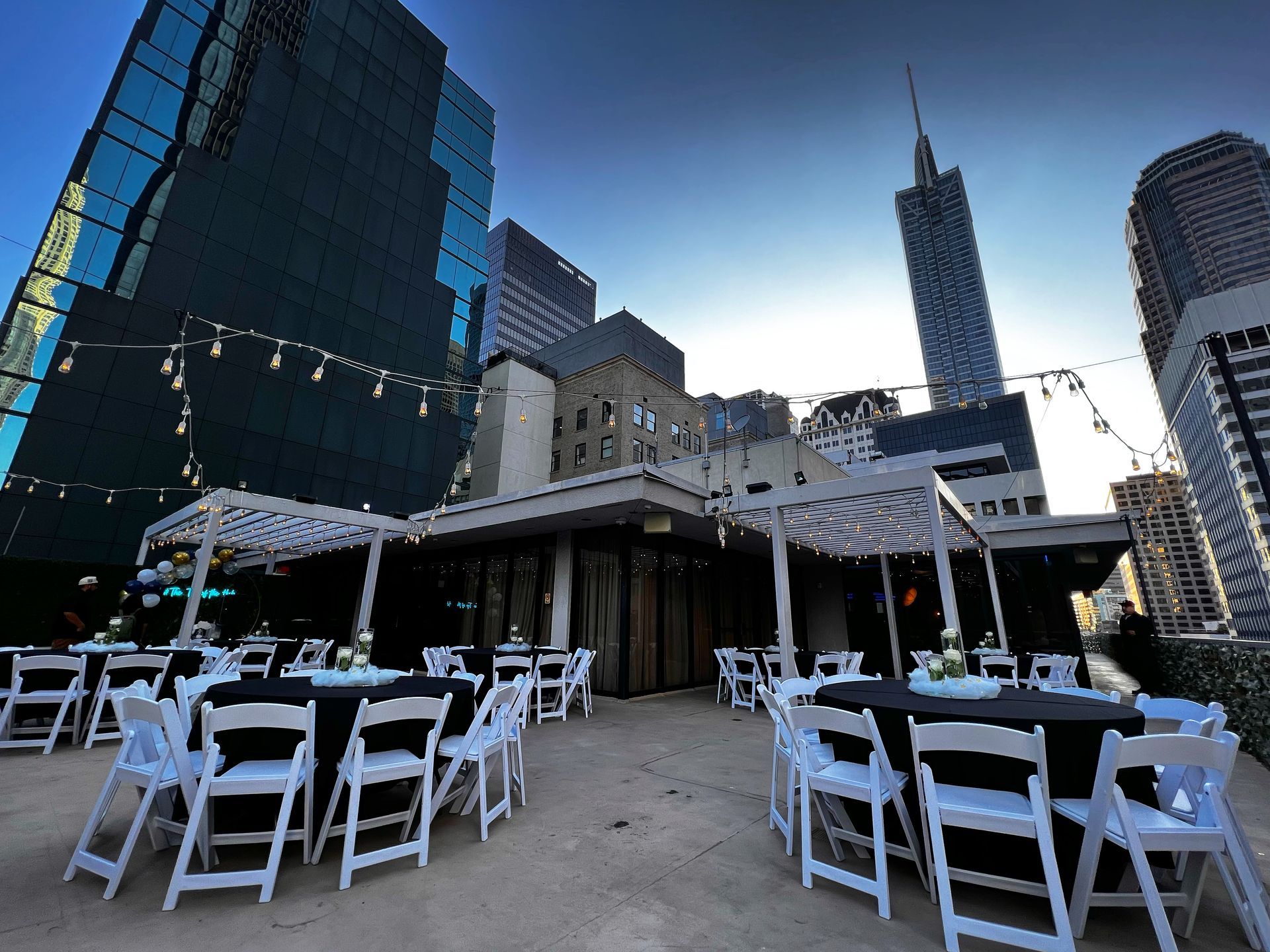 Tables and chairs are set up in front of tall buildings