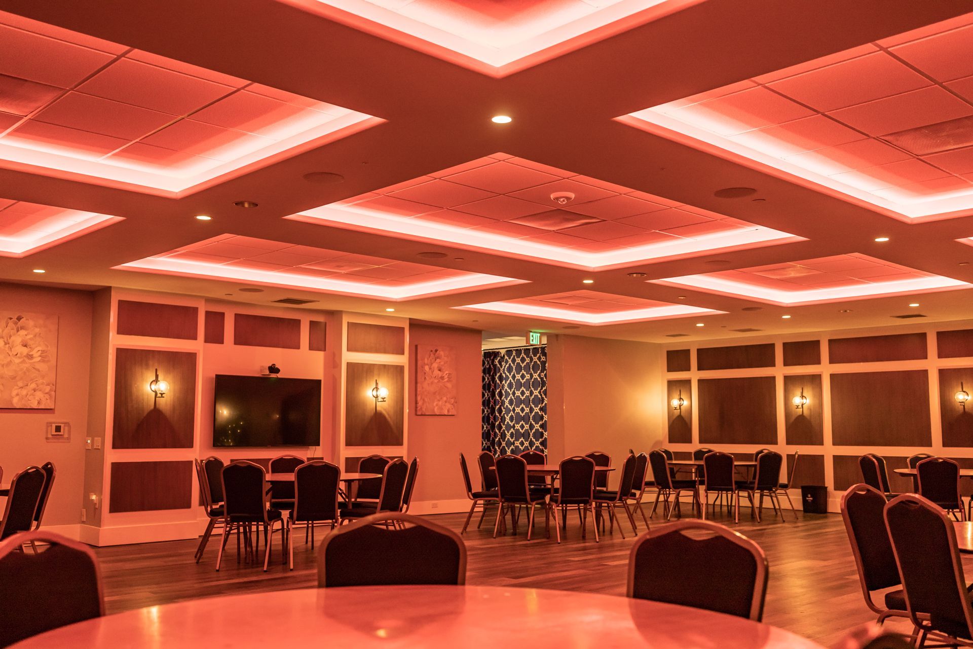 A large room with tables and chairs and red lights on the ceiling.