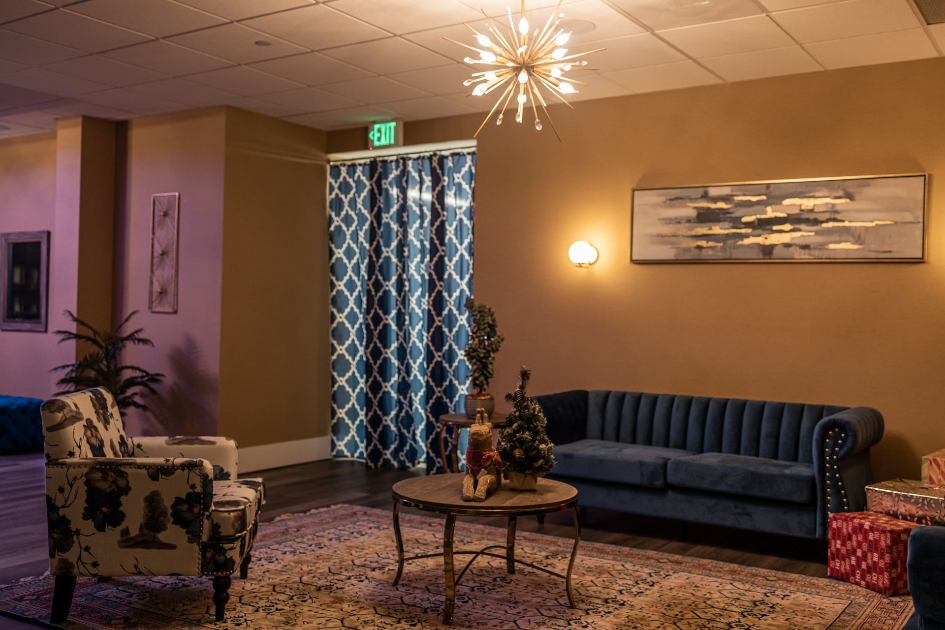 A living room with a couch and chairs and an exit sign