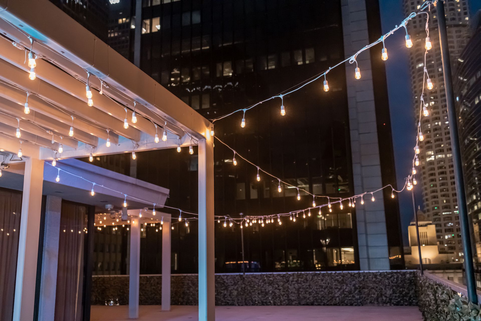 A string of lights is hanging from a pergola at night.