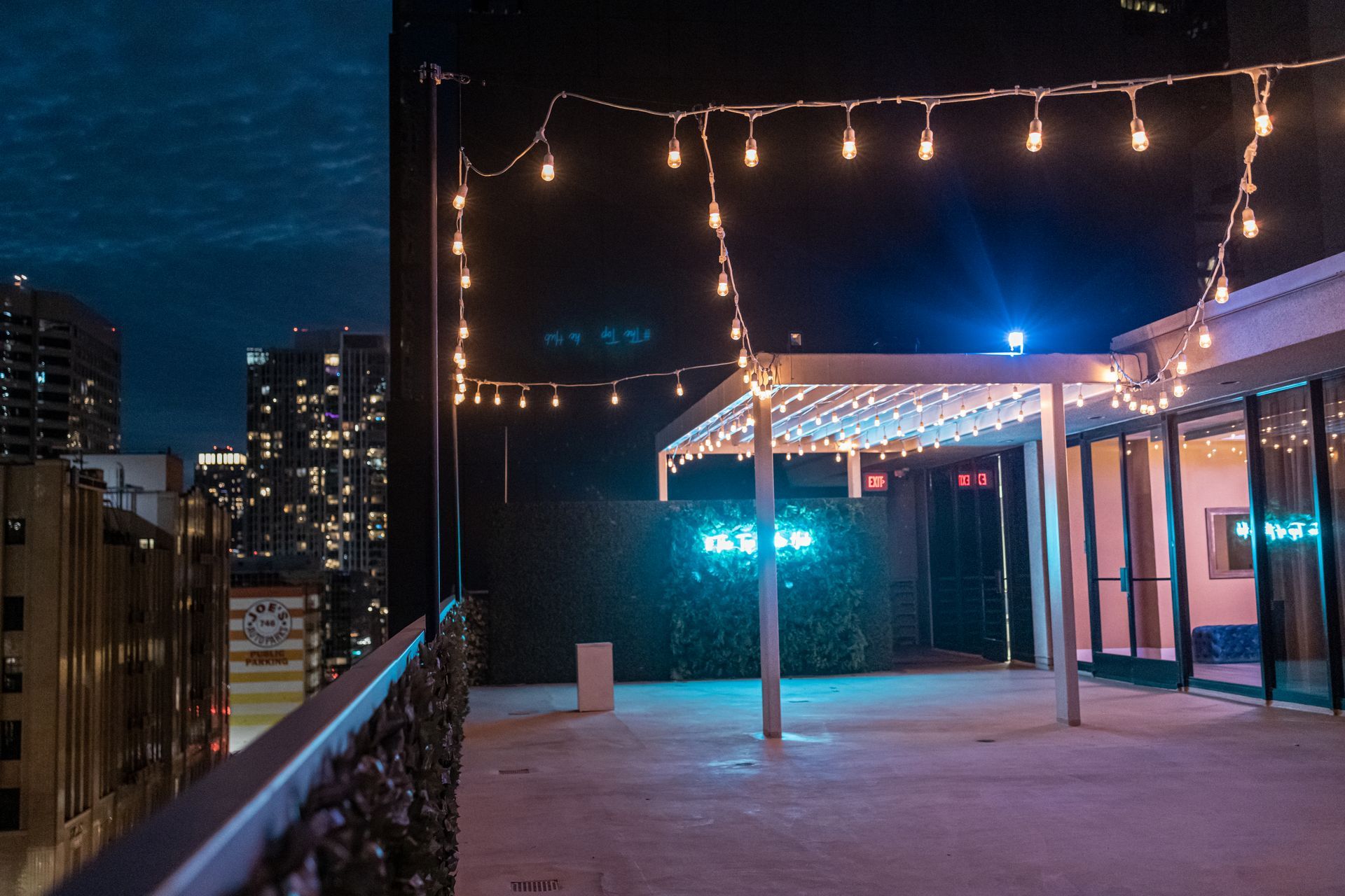 A rooftop with christmas lights and a city in the background