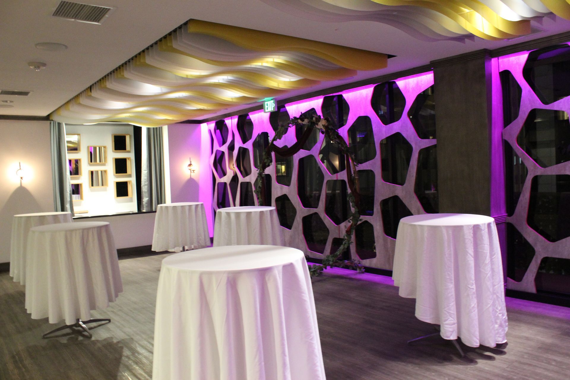 A room with tables and purple lights on the wall.