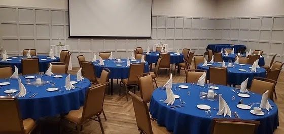 A large room filled with tables and chairs and a projector screen.