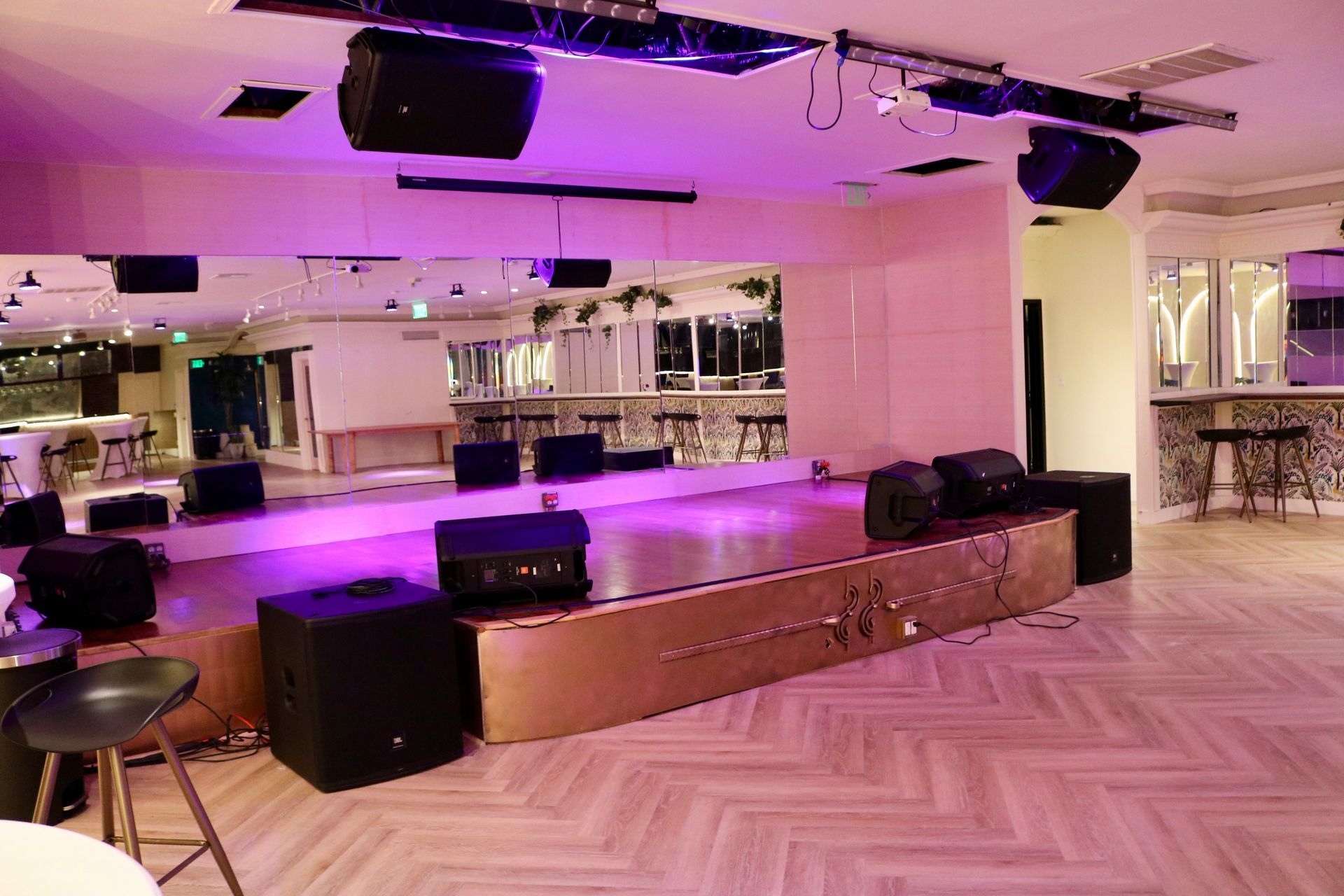 Empty stage with purple lighting in a mirrored banquet hall and herringbone wood floor