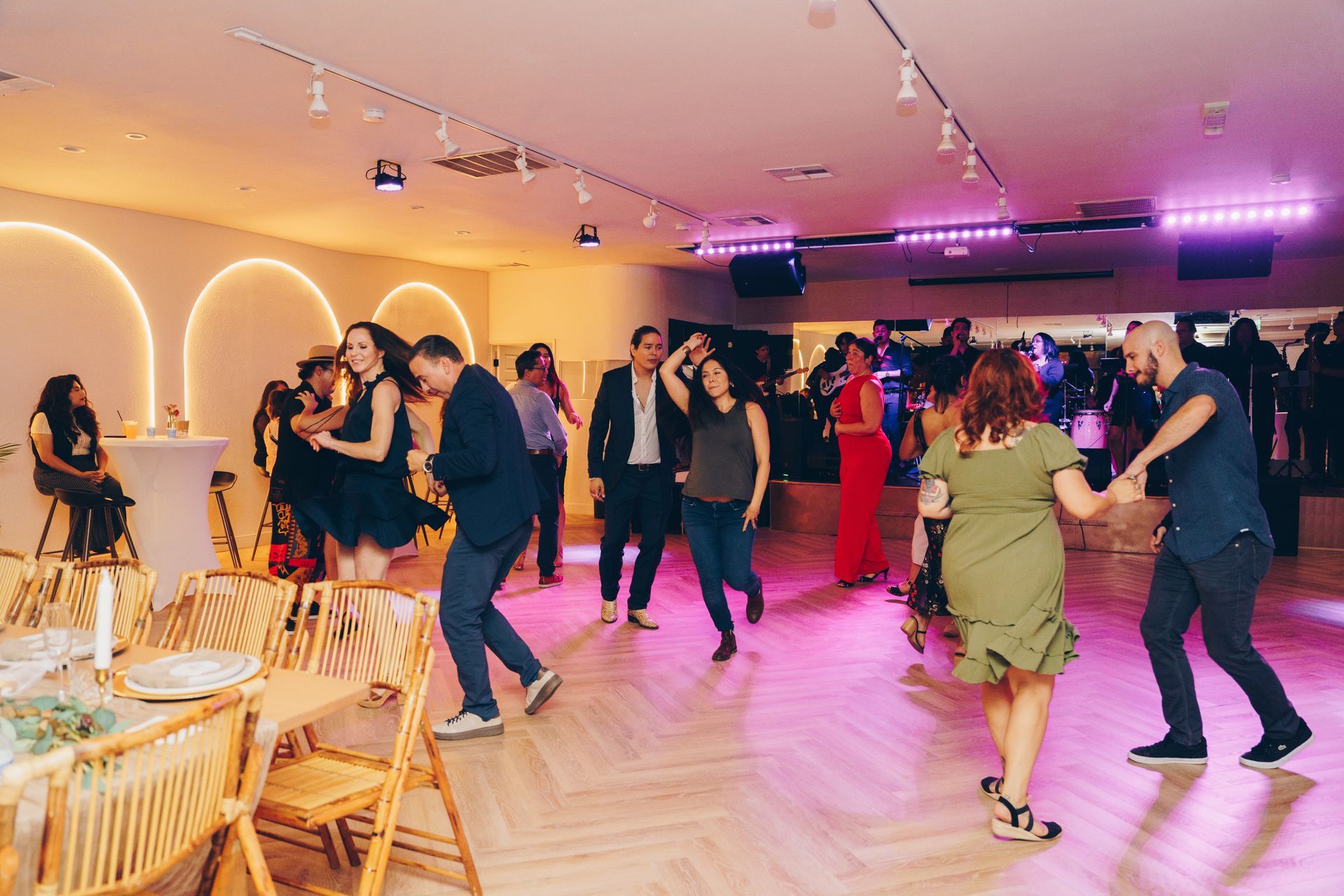 Guests dancing at a lively indoor event with warm lights and a wooden floor