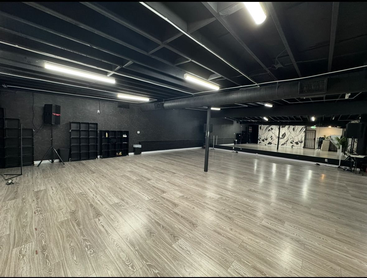 An empty dance studio with a wooden floor and black walls