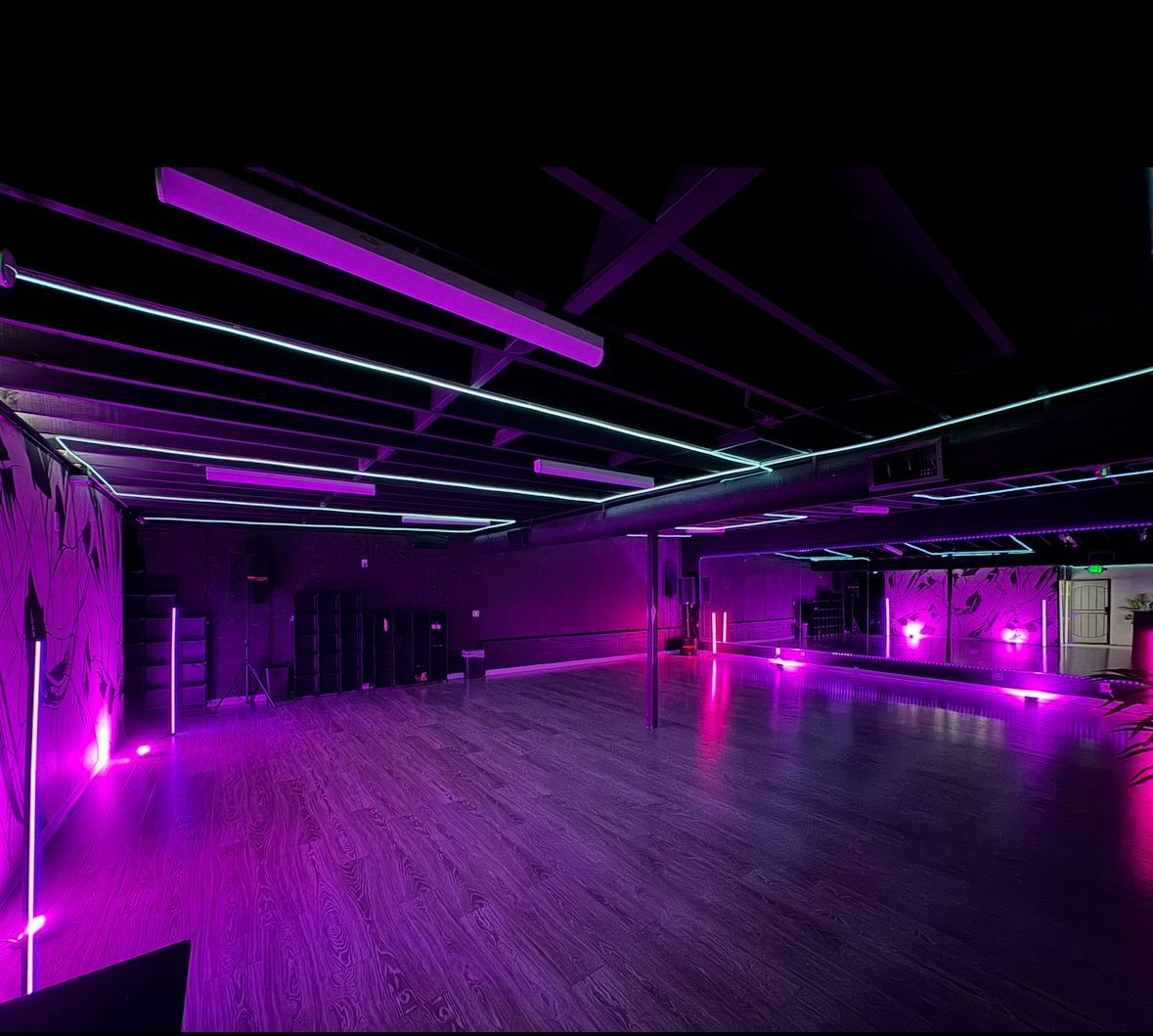 A large empty room with purple lights on the ceiling and floor.
