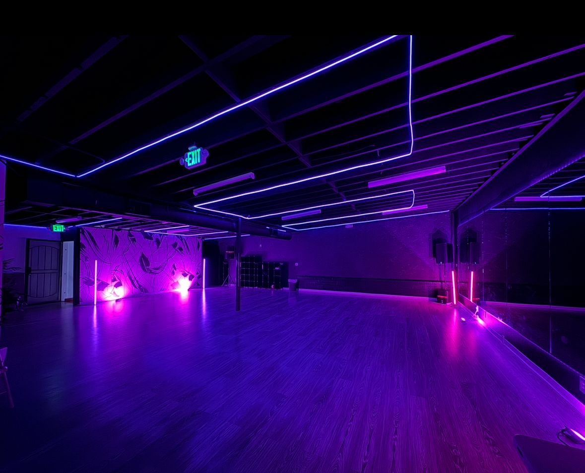 An empty dance studio with purple lights on the floor and ceiling.