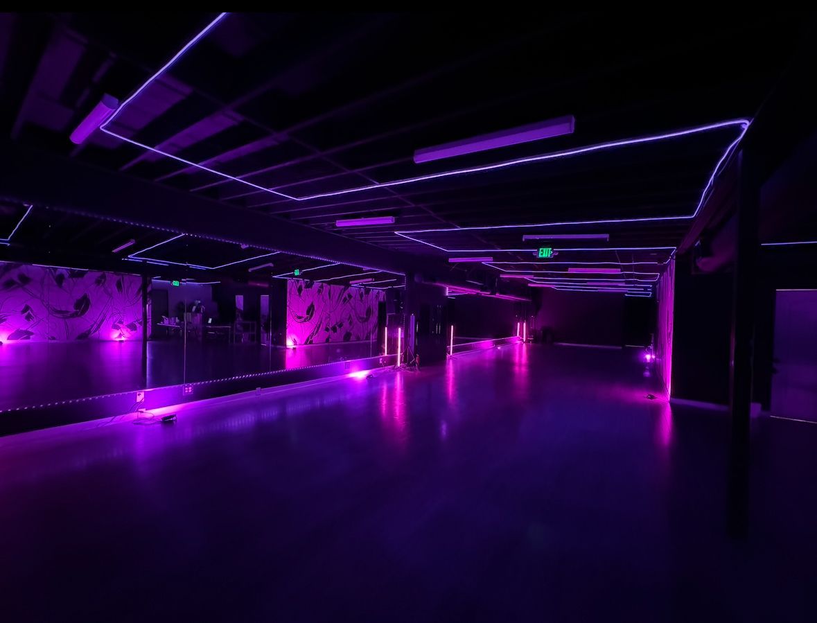 A large empty room with purple lights on the ceiling.