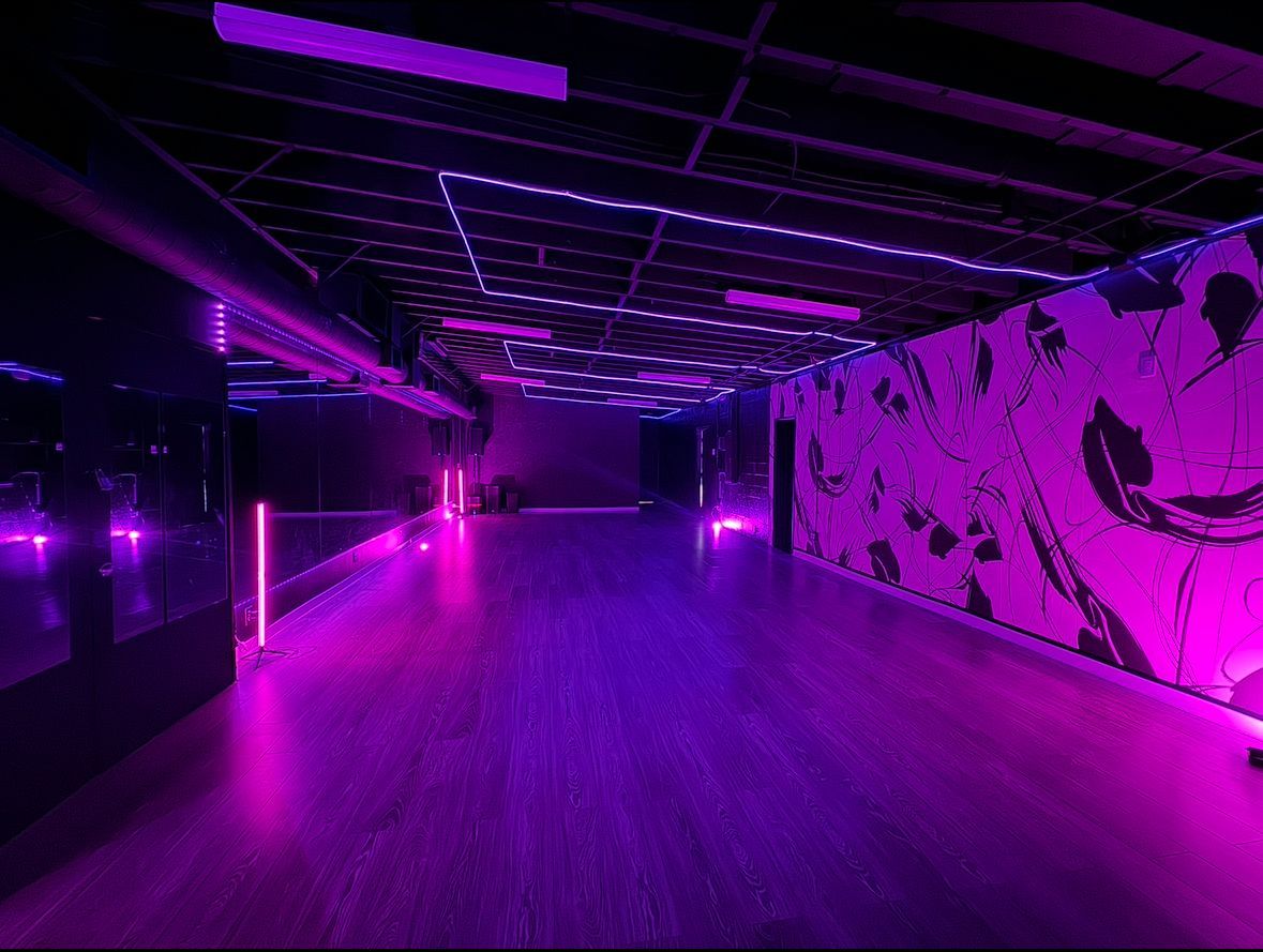 An empty dance studio with purple lights on the walls and floor.