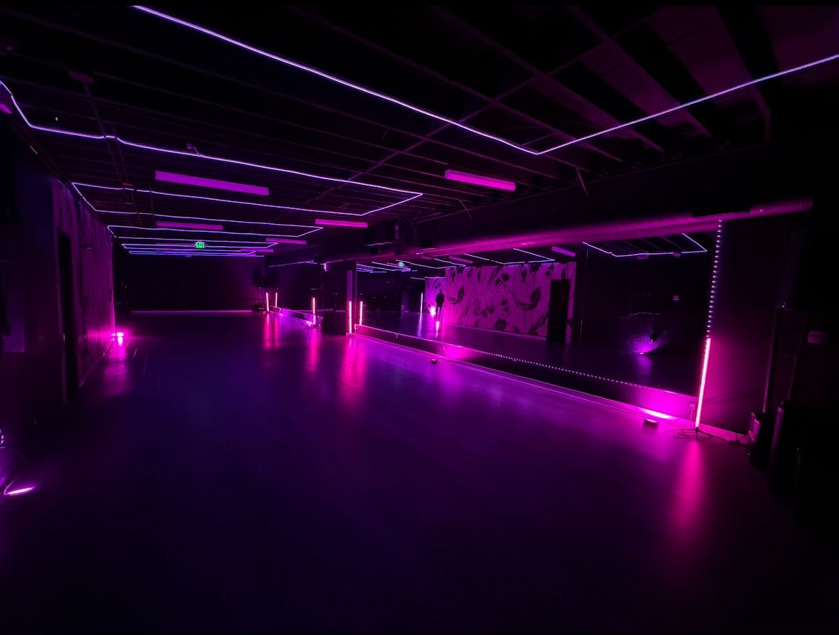 A large empty room with purple lights on the walls and floor.