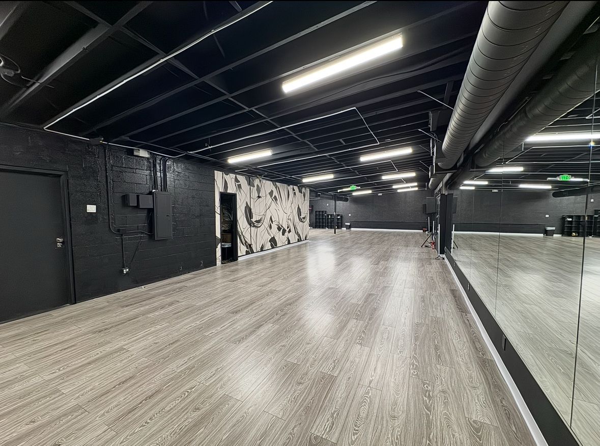 A large empty dance studio with a large mirror on the wall.