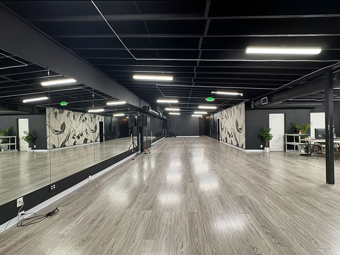 A large empty dance studio with a lot of mirrors on the wall.