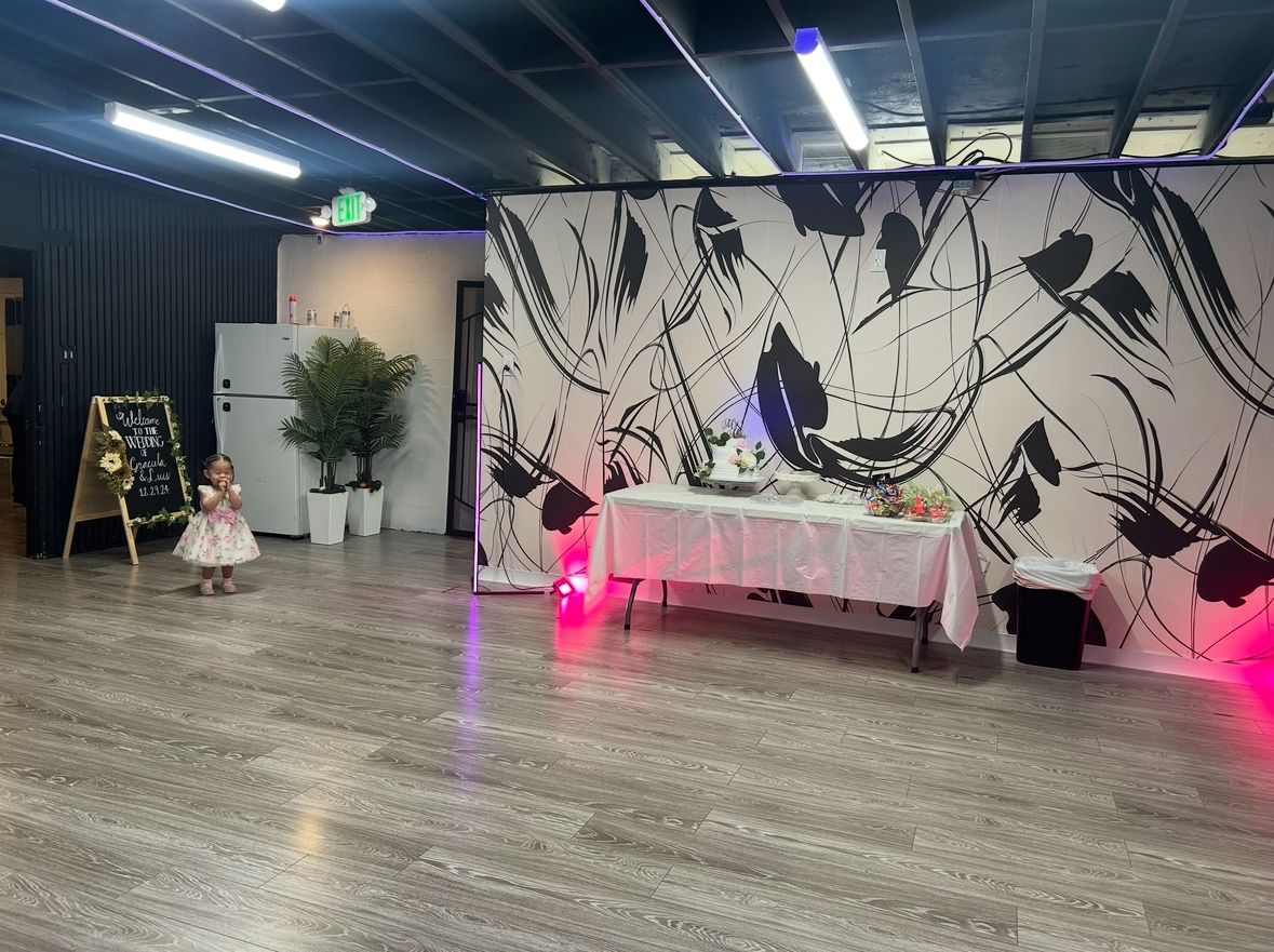 A little girl is standing in a room with a table and a wall.