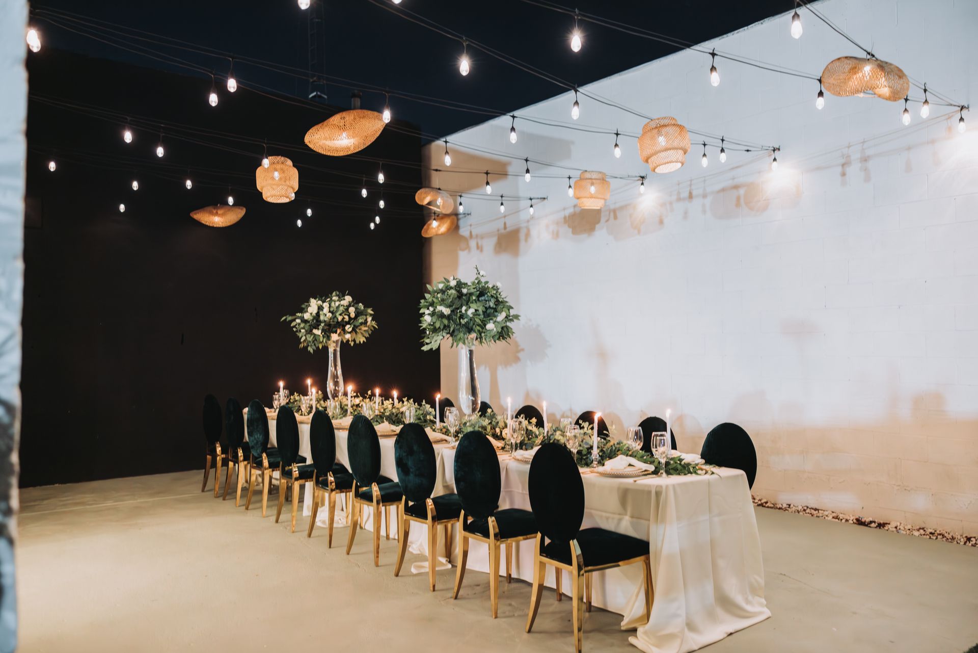 A long table and chairs in a room with candles hanging from the ceiling.