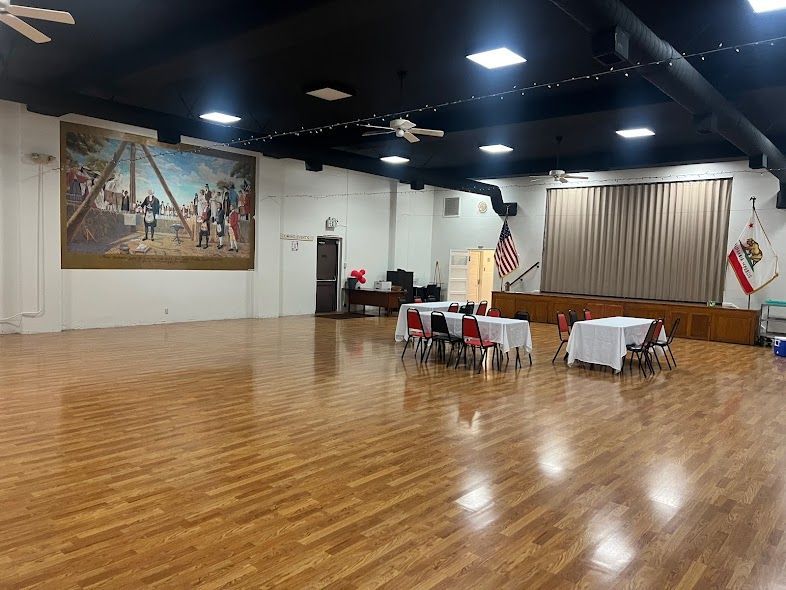 A large room with wooden floors and tables and chairs in it.