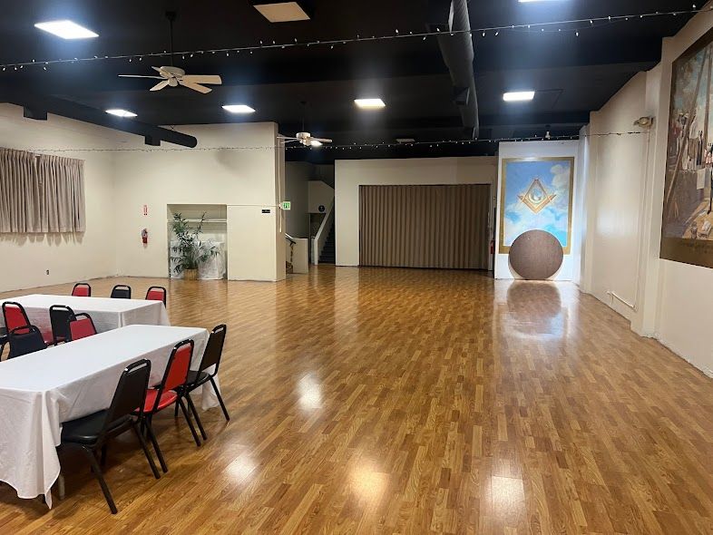 A large room with wooden floors and tables and chairs.