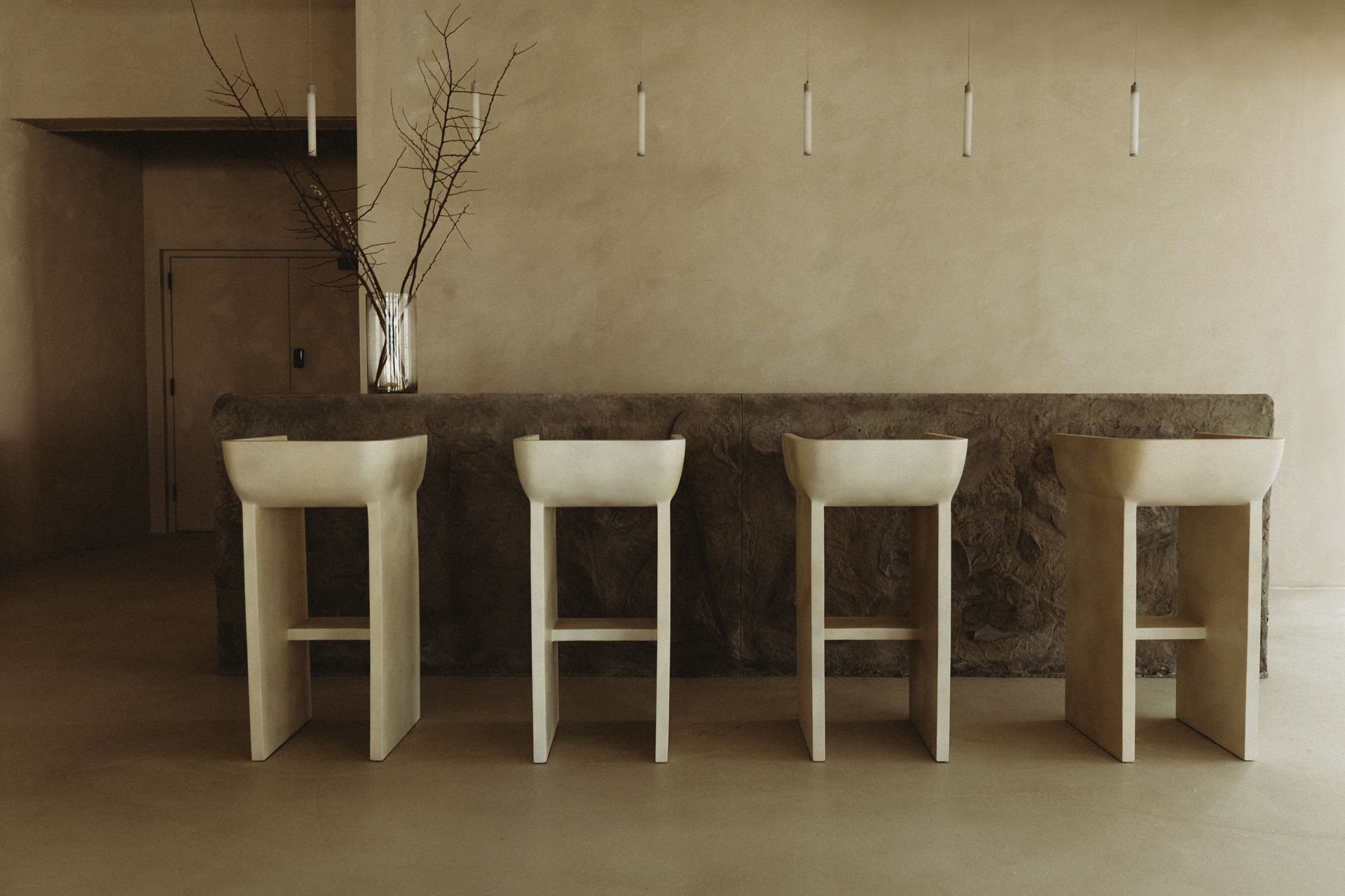 A bathroom with a row of sinks and stools