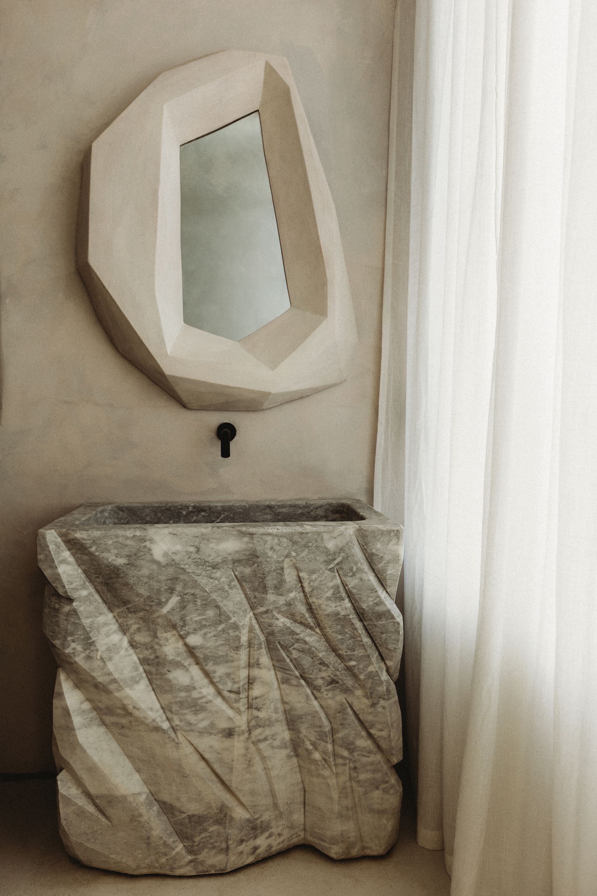 A bathroom with a stone sink and a mirror on the wall.