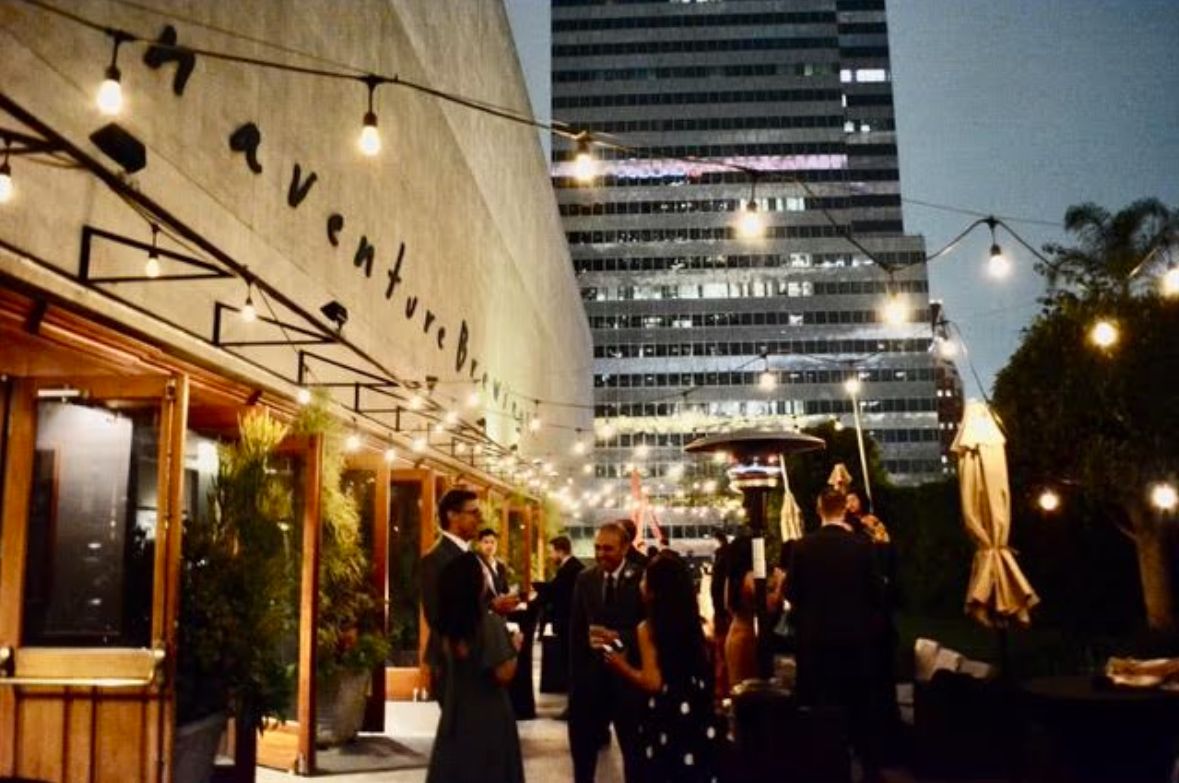 A group of people are standing outside of a restaurant at night.