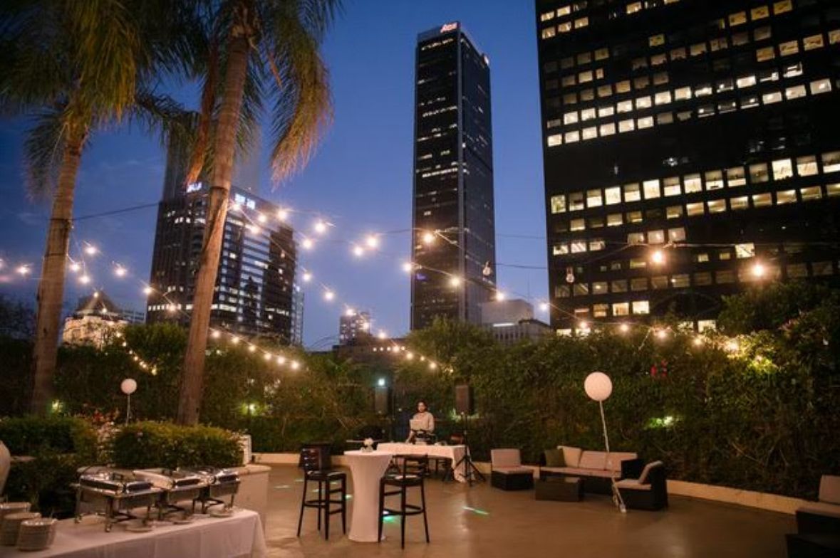 A patio with tables and chairs in front of a city skyline at night.